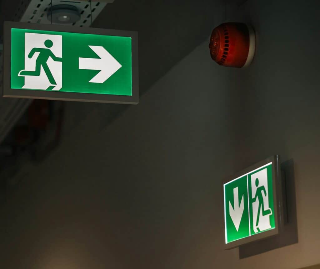 Emergency exit signage beneath mezzanine floor, complying with building regulations and fire safety requirements