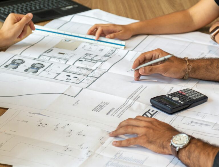 Architects planning mezzanine floor layout with blueprints and calculator during workspace design consultation