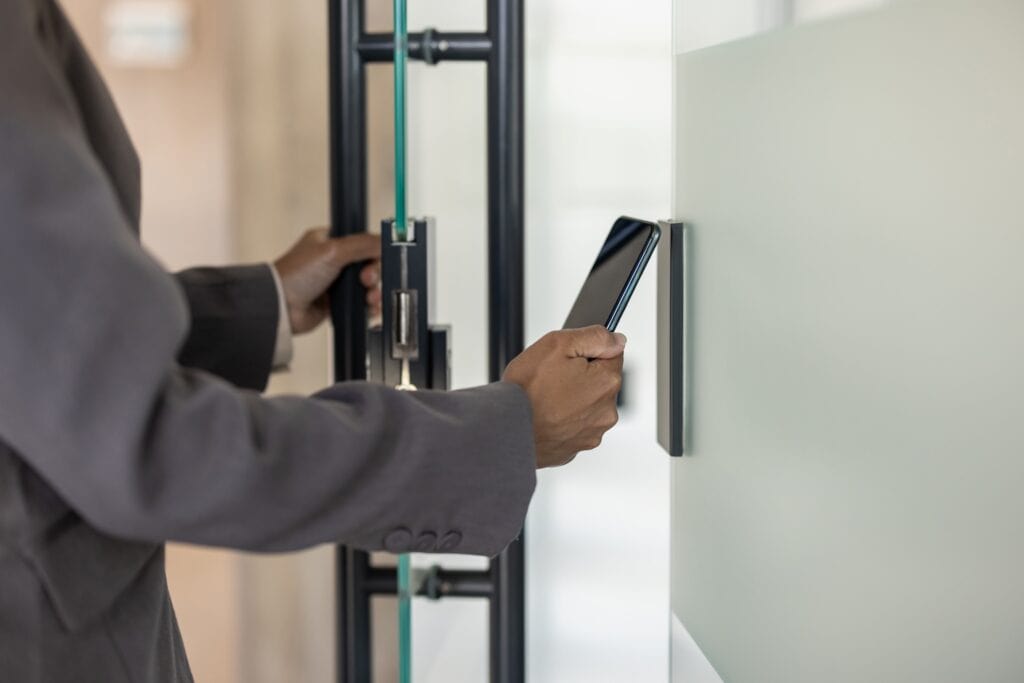 Professional using smartphone for smart office access control system and keyless entry technology integration